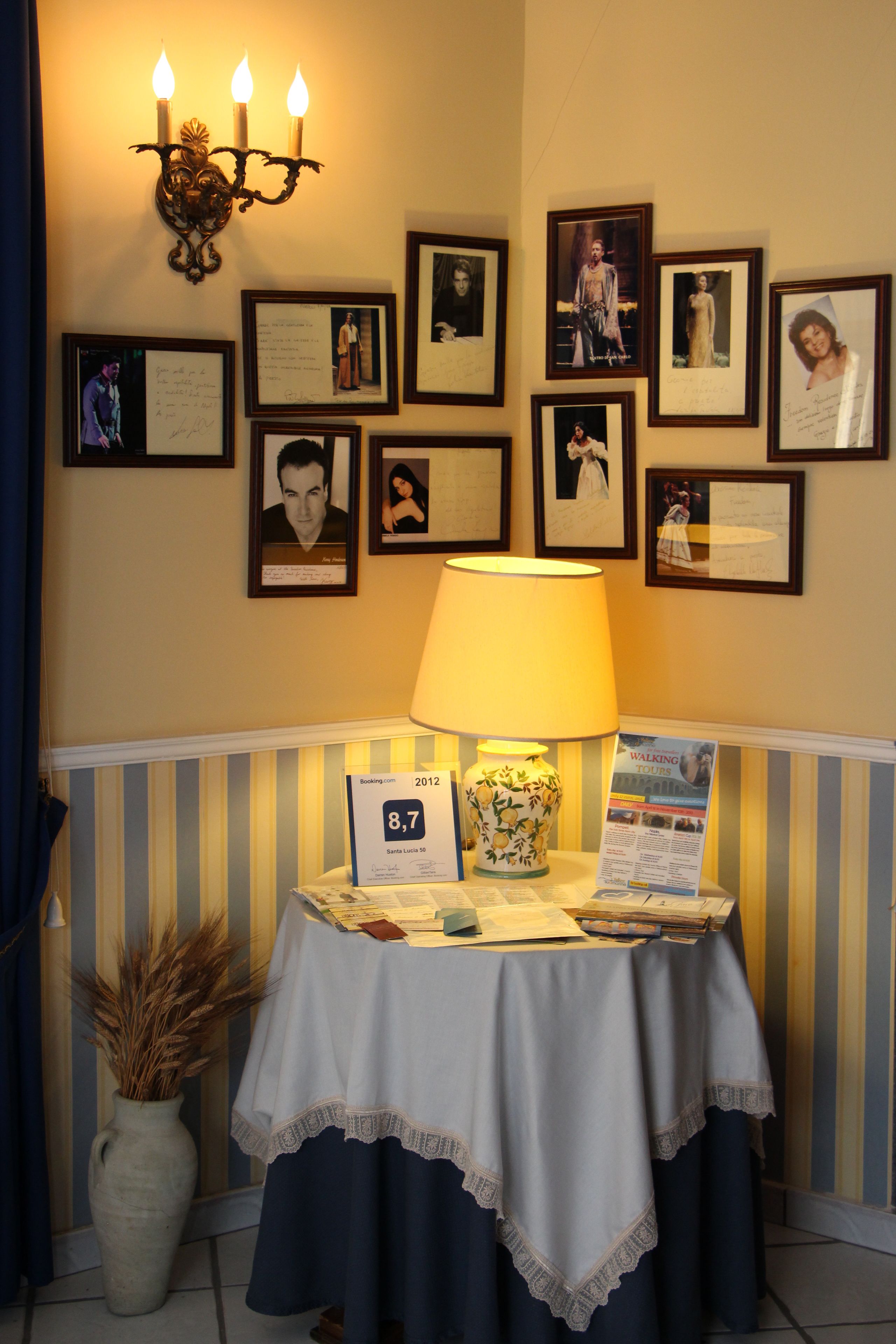 Ein Empfangsbereich mit einem Tisch, auf dem ein Schild, eine Lampe und gerahmte Fotos an der Wand stehen.