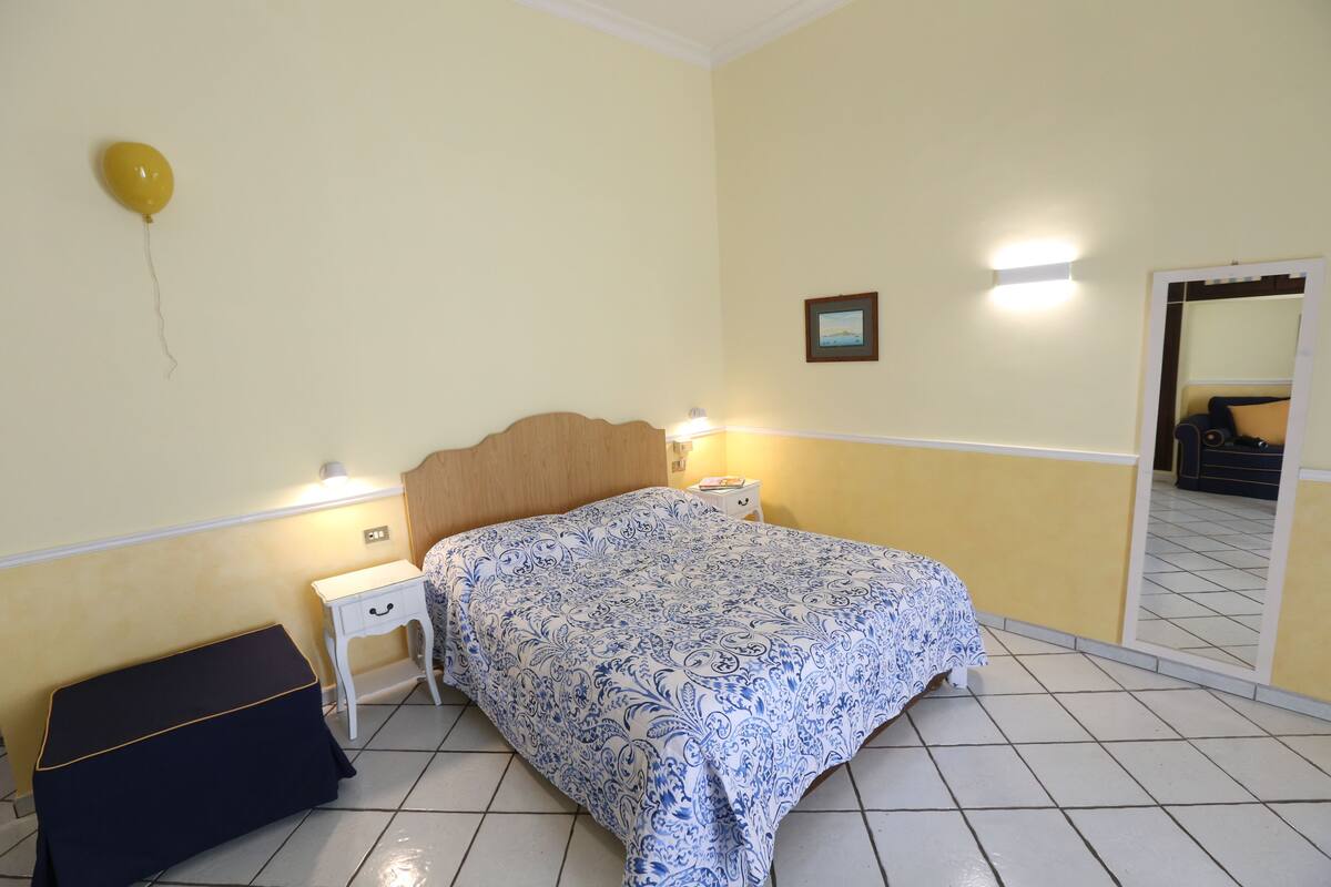 Un dormitorio con cama, mesitas de noche, un espejo y un globo en la pared.
