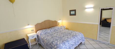 A bedroom with a bed, bedside tables, a mirror, and a balloon on the wall.