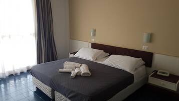 Camera d'albergo con un letto grande, due comodini e una finestra con tende.