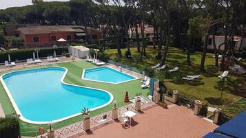Una piscina dalla forma particolare, circondata da un'area verde e lettini da relax.