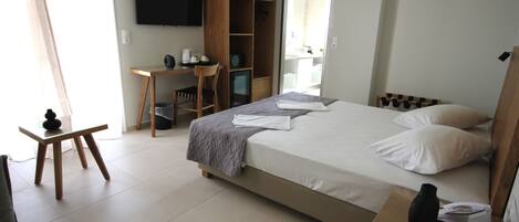 Una habitación de hotel con cama, escritorio, silla, armario y televisión.