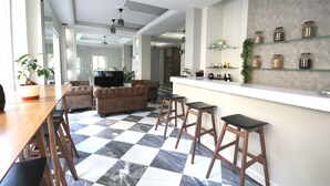 A modern kitchen with a checkered floor, wooden bar stools, and a countertop with jars. - Mirabello Hotel (Heraklion)