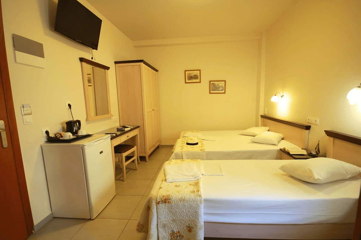 Une chambre d’hôtel avec deux lits, un bureau, un réfrigérateur, une télévision et un miroir.