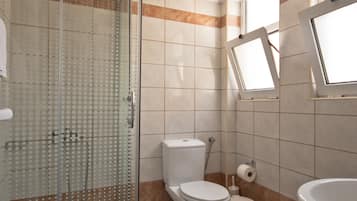 Un bagno con doccia in vetro, un water, un bidet e un lavandino.