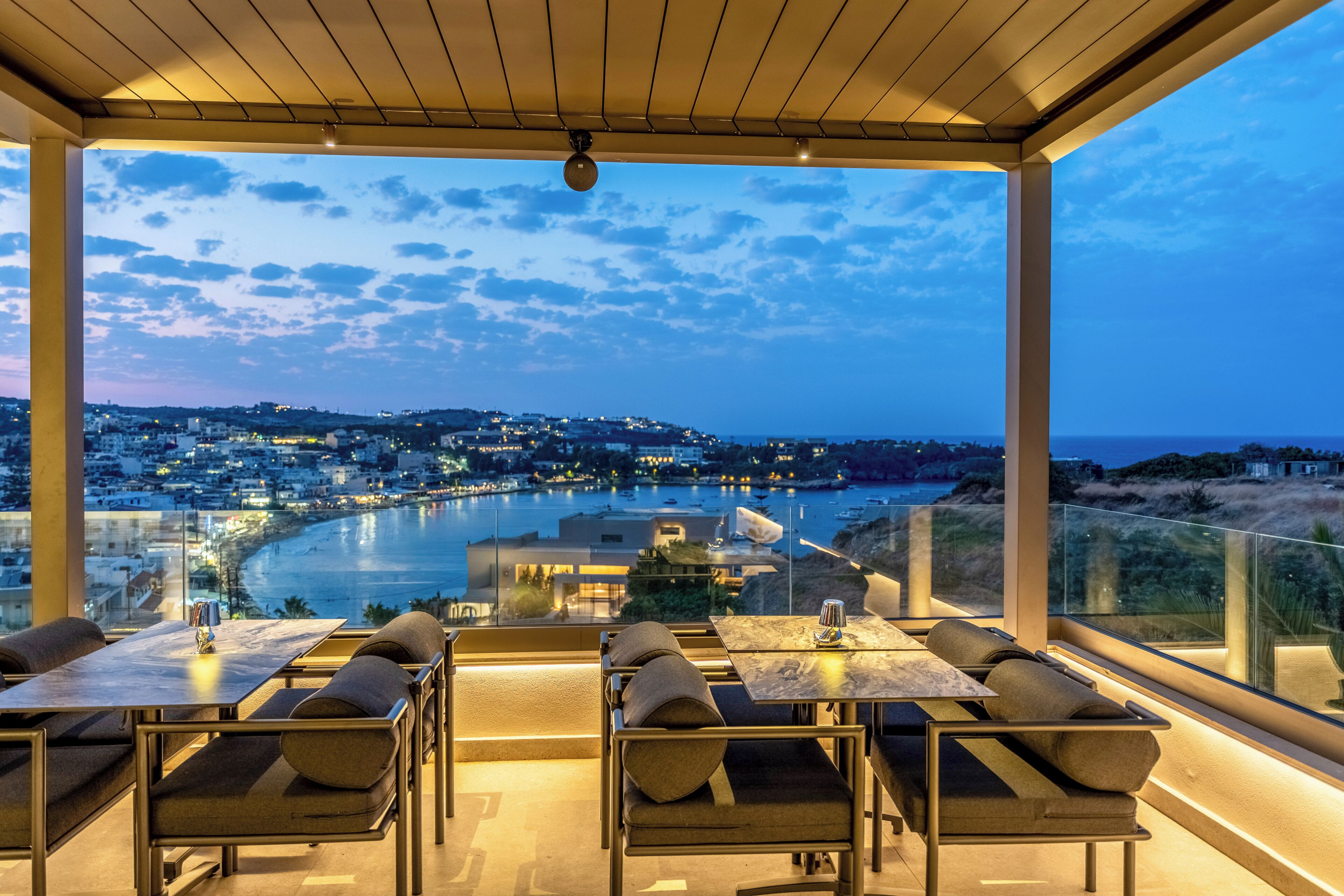 A terrace with outdoor seating overlooking a waterfront cityscape.