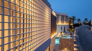 A modern hotel with a grid-patterned facade, a pool area, and palm trees. - Scala Boutique Hotel & Suites – Adults Only (Malevizi)