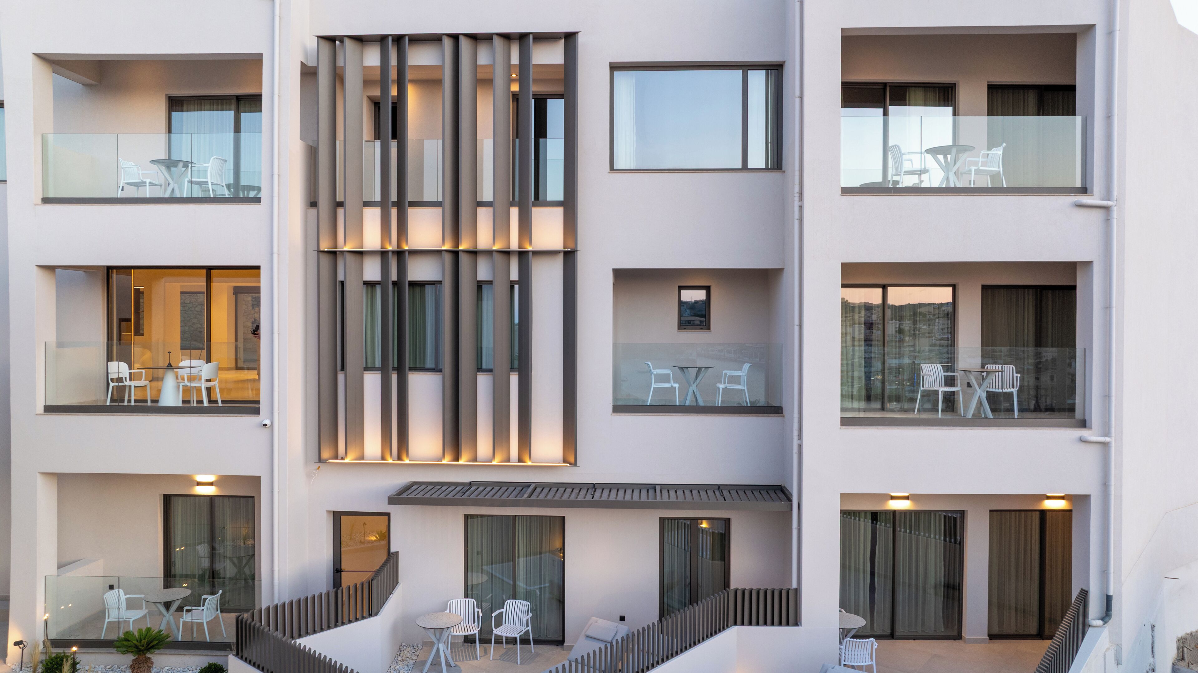 A multi-story hotel with balconies, outdoor seating, and a modern architectural design.