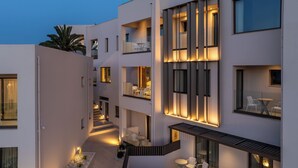 A modern multi-story building with balconies, outdoor seating, and a central staircase. - Scala Boutique Hotel & Suites – Adults Only (Malevizi)