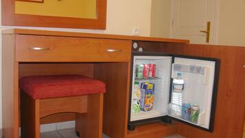 A compact kitchenette with a built-in refrigerator, a small bench, and a door with a no-smoking sign.