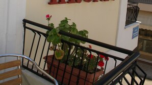 A sign for Hotel Kronio with a balcony railing and potted plants. - Kronio (Archaia Olympia)