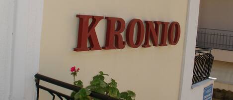 Señal de Hotel Kronio con baranda de balcón y plantas en macetas.