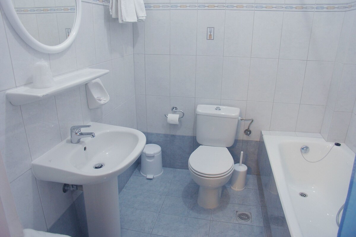 A bathroom with a sink, toilet, bidet, and bathtub.