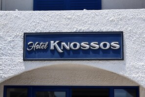 Letrero de hotel con el nombre 'Hotel Knossos' sobre una pared con textura.