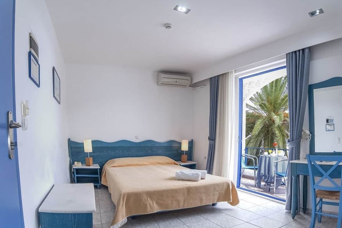 Habitación de hotel con cama, escritorio, silla y vistas al exterior.