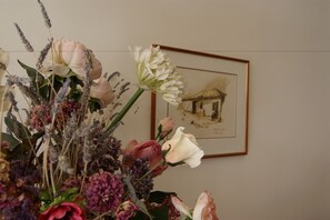 A floral arrangement with a framed picture of a building on the wall. - Hotel Pelops (Archaia Olympia)