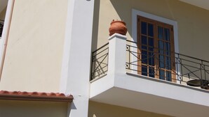 Een hotel met een witte gevel, terracotta dakpannen en een balkon met een sierhekwerk.
