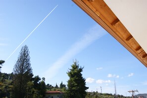 A clear sky with a contrail, a wooden structure, and a building with a red roof. - Hotel Pelops (Archaia Olympia)