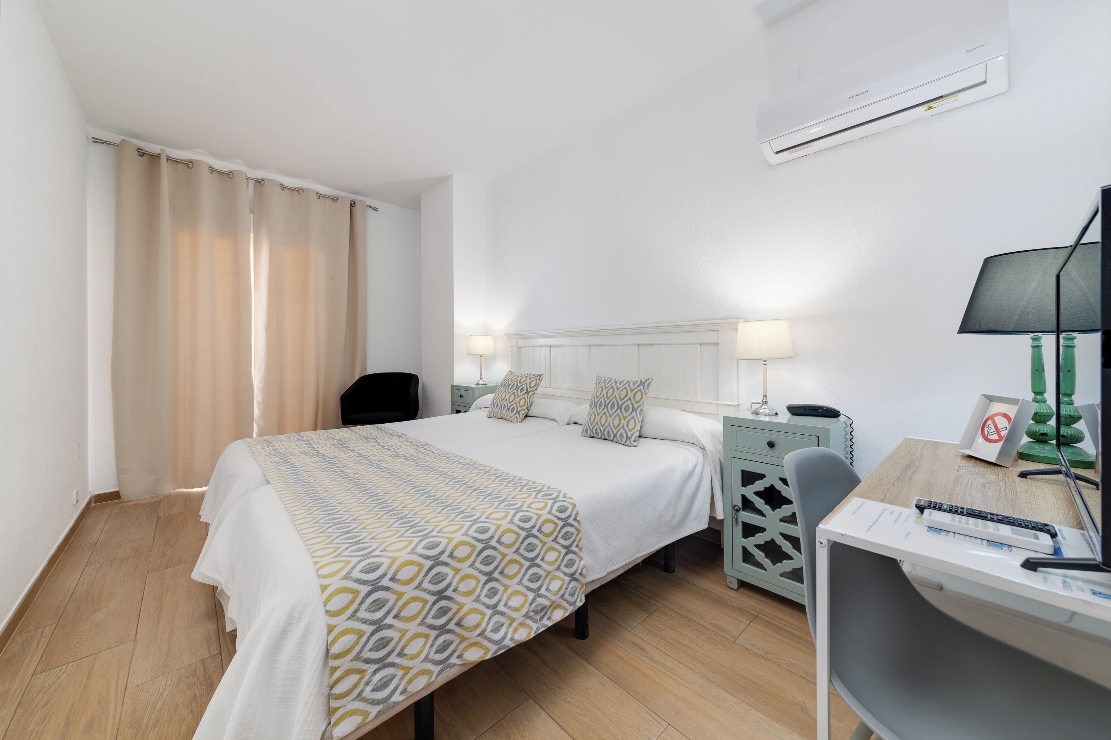 A hotel room with a bed, bedside tables, a desk, and a chair.