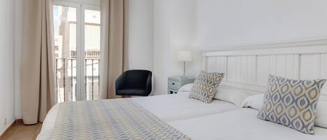 Habitación de hotel con una cama grande, una silla, una mesita de noche y una ventana con cortinas.