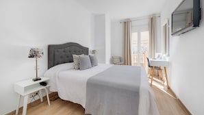 A modern hotel room with a large bed, a bedside table with a lamp, a desk with a chair, and a TV mounted on the wall. - Hotel Madrid (Torrevieja)