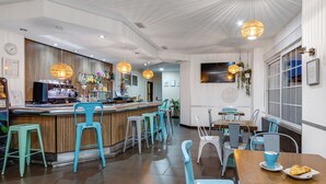 A cafe with a bar area, seating, and a clock on the wall. - Hotel Madrid (Torrevieja)