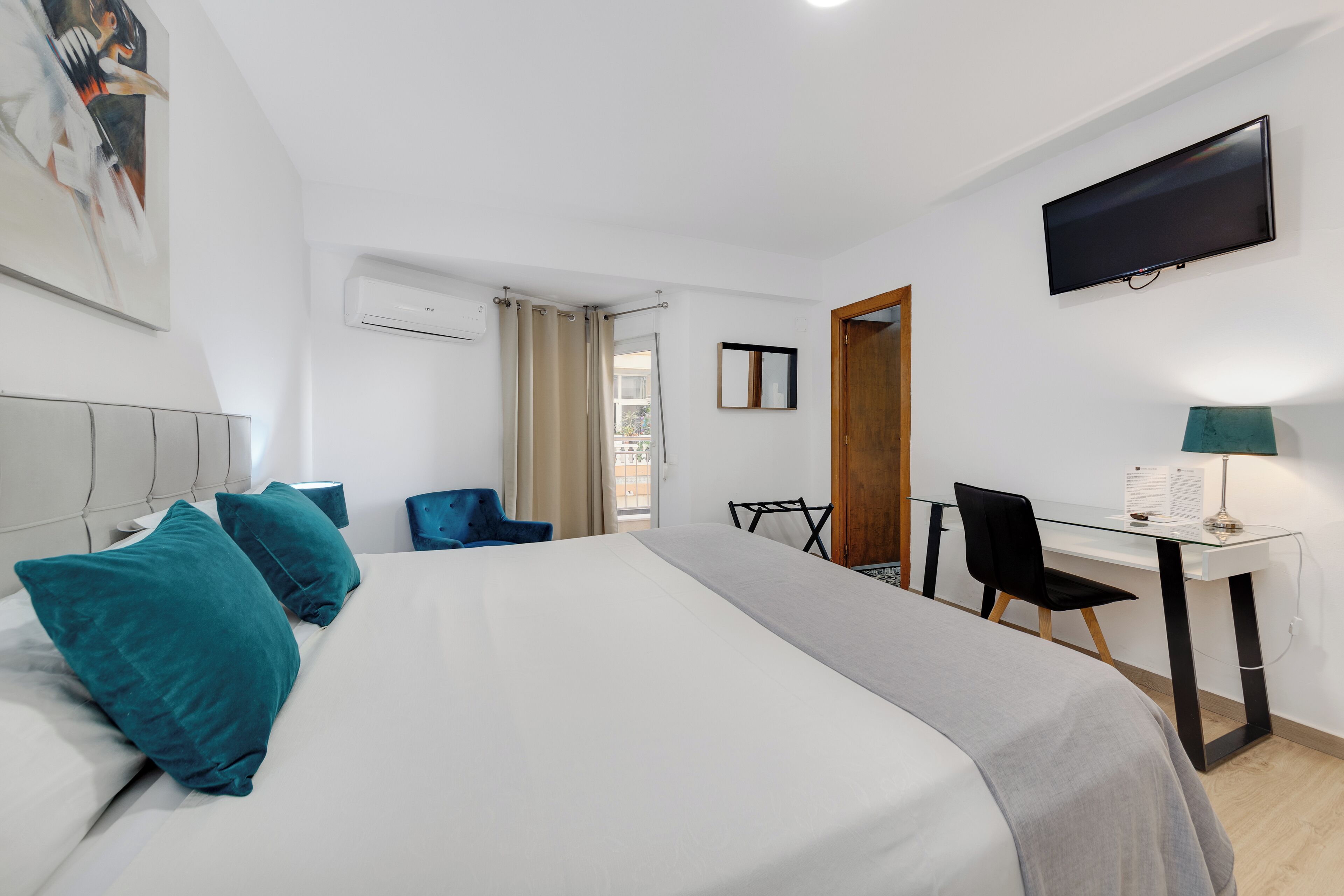 Une chambre d’hôtel avec un grand lit, un bureau, une chaise, une télévision et un appareil de climatisation.