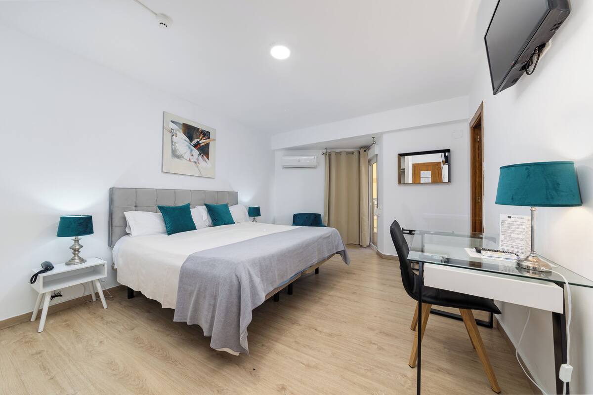 A modern hotel room with a bed, a desk, and a TV.