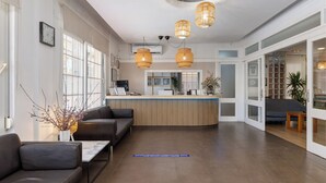 A modern reception area with a wooden reception desk, leather seating, and rattan pendant lighting. - Hotel Madrid (Torrevieja)