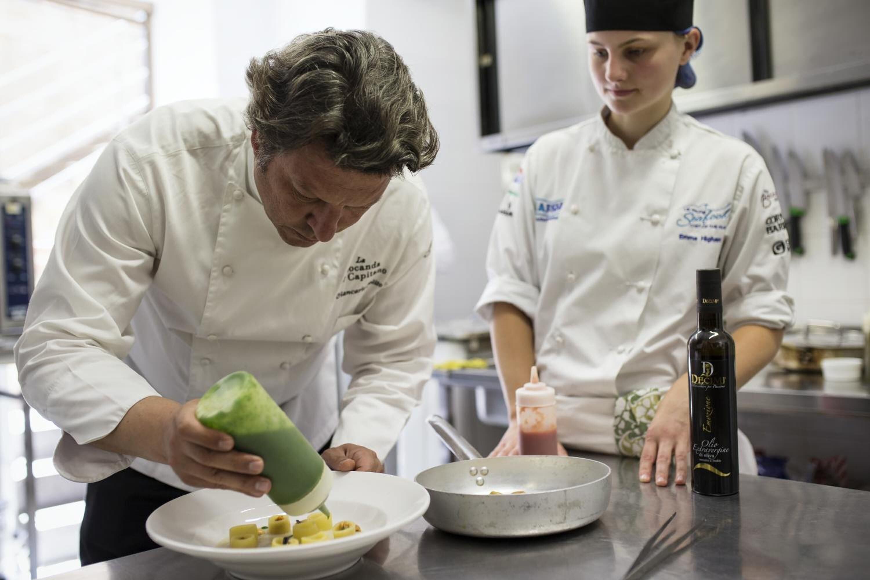 Two chefs in a kitchen preparing food.