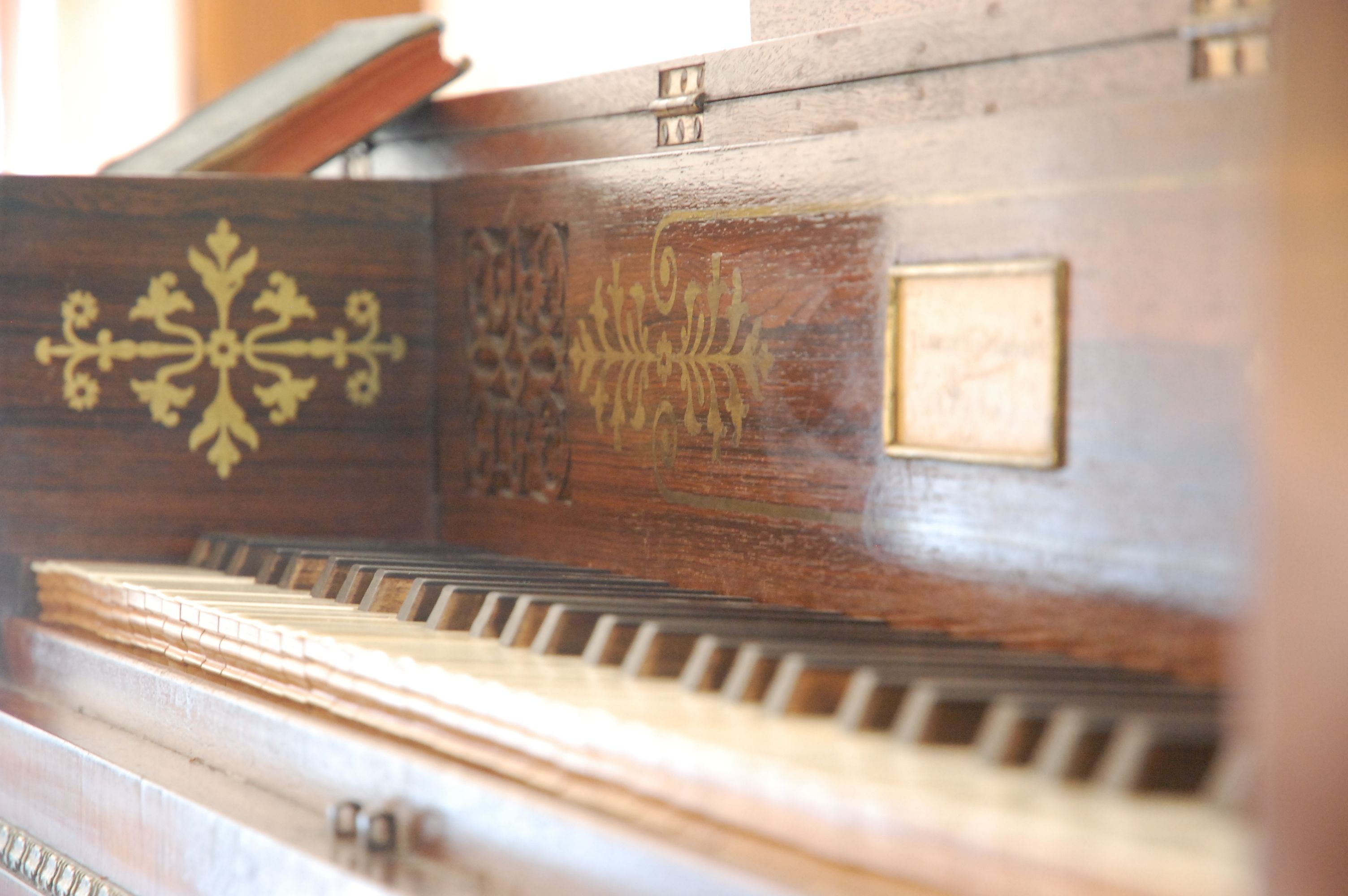A close-up of a piano with intricate designs and a plaque.