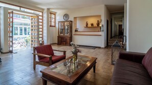 A spacious living area with a wooden coffee table, a red armchair, a brown sofa, and a glass-top coffee table with a vase. - Hercules (Archaia Olympia)