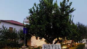 A sign for Hotel Hercules with a large tree in the foreground. - Hercules (Archaia Olympia)