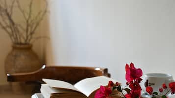 A book, a cup, and a vase with flowers on a table.