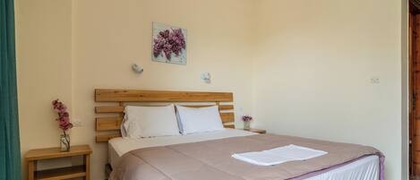 A bedroom with a wooden bed, a nightstand, a vase with flowers, and a wall-mounted air conditioner.