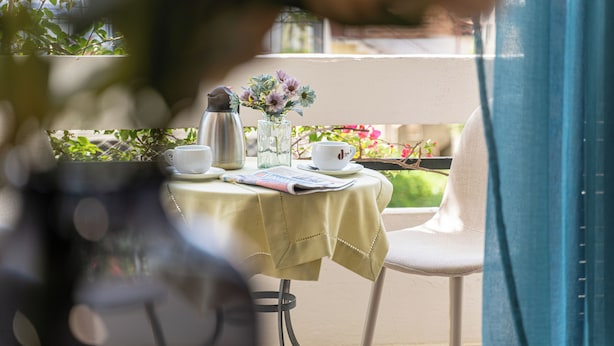 A table with a newspaper, a coffee pot, and a vase with flowers. - Hercules (Archaia Olympia)