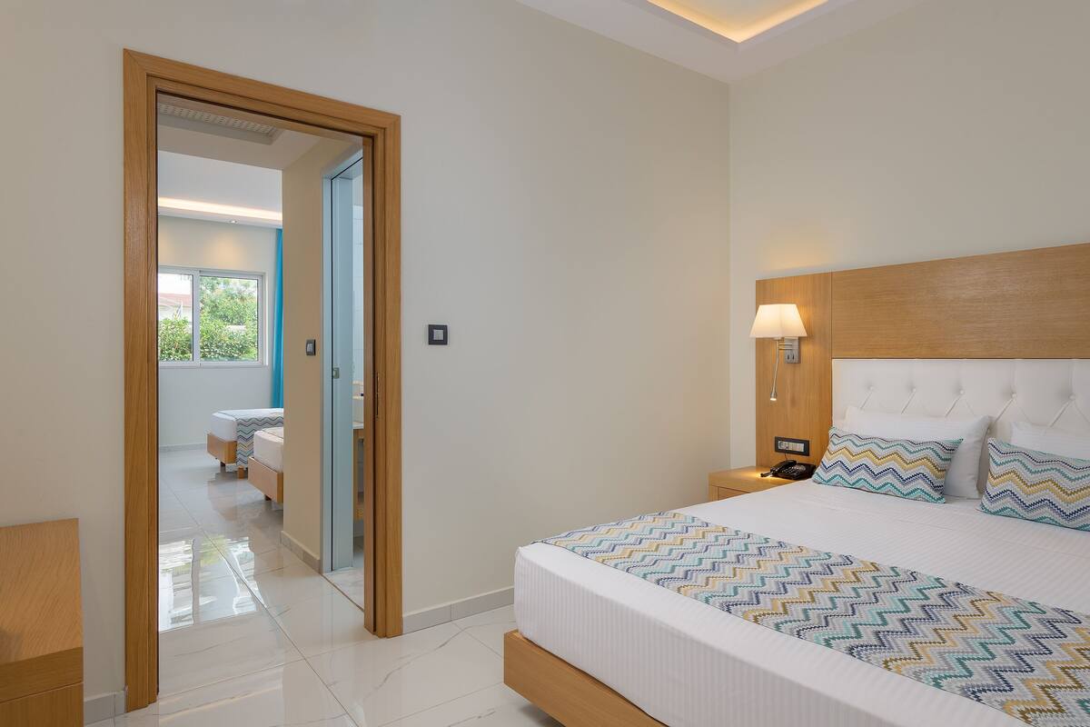 A modern bedroom with a large bed, a wooden headboard, and a nightstand with a lamp.