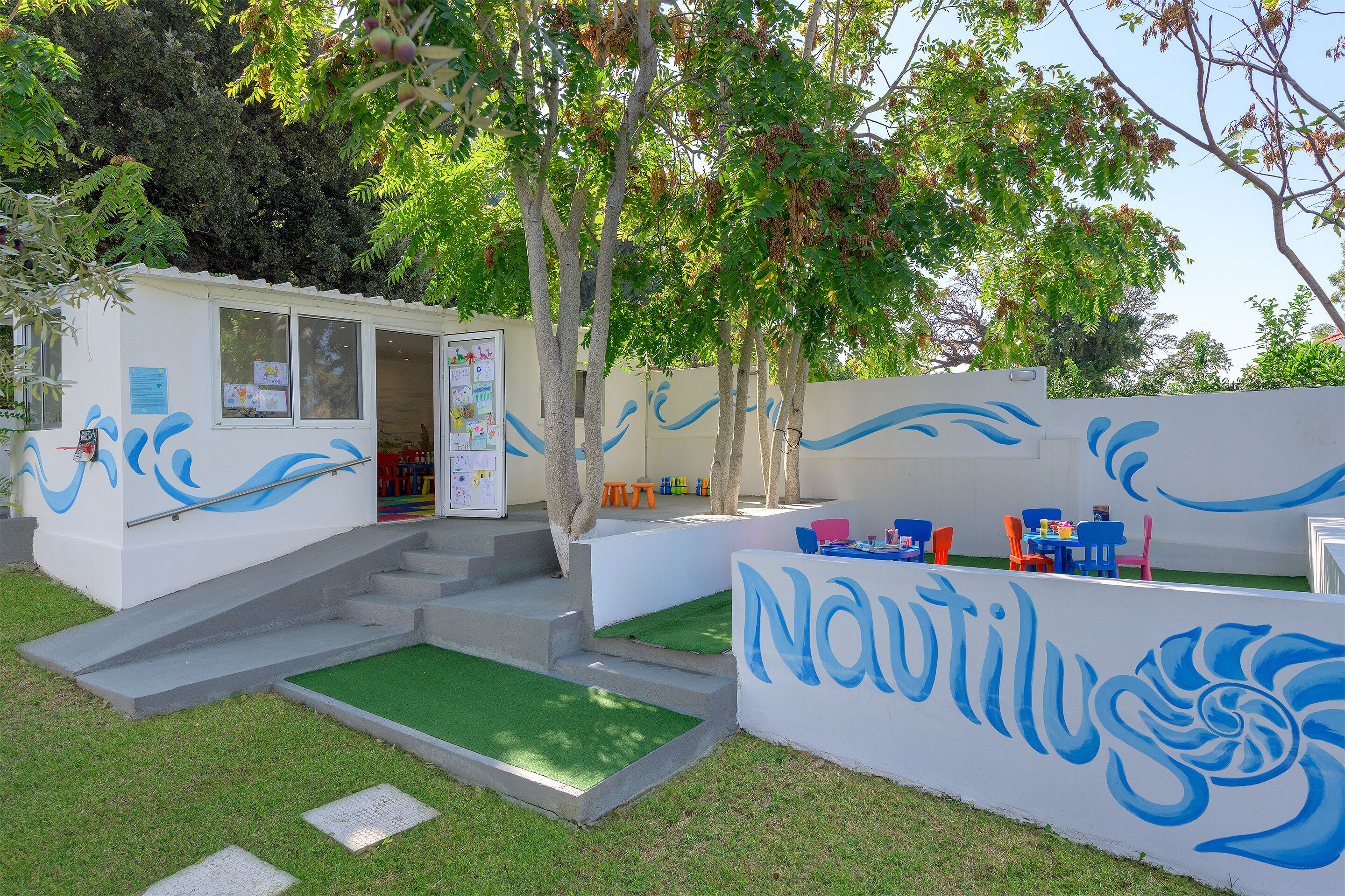 A building with a mural, outdoor seating, and steps leading to an entrance.