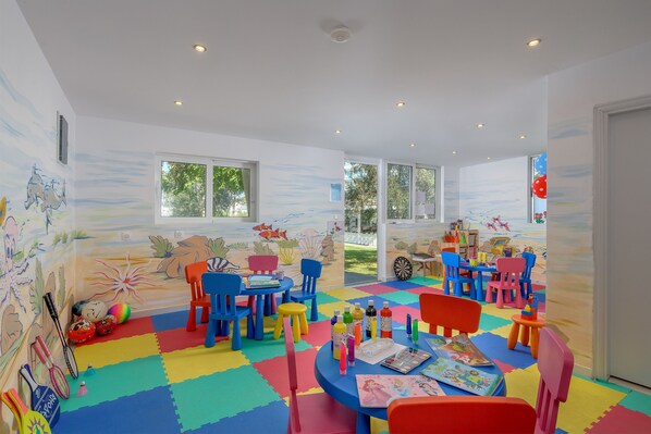 Une salle de jeux pour enfants aux couleurs vives, avec des meubles colorés et une fresque murale sur le thème de la plage.