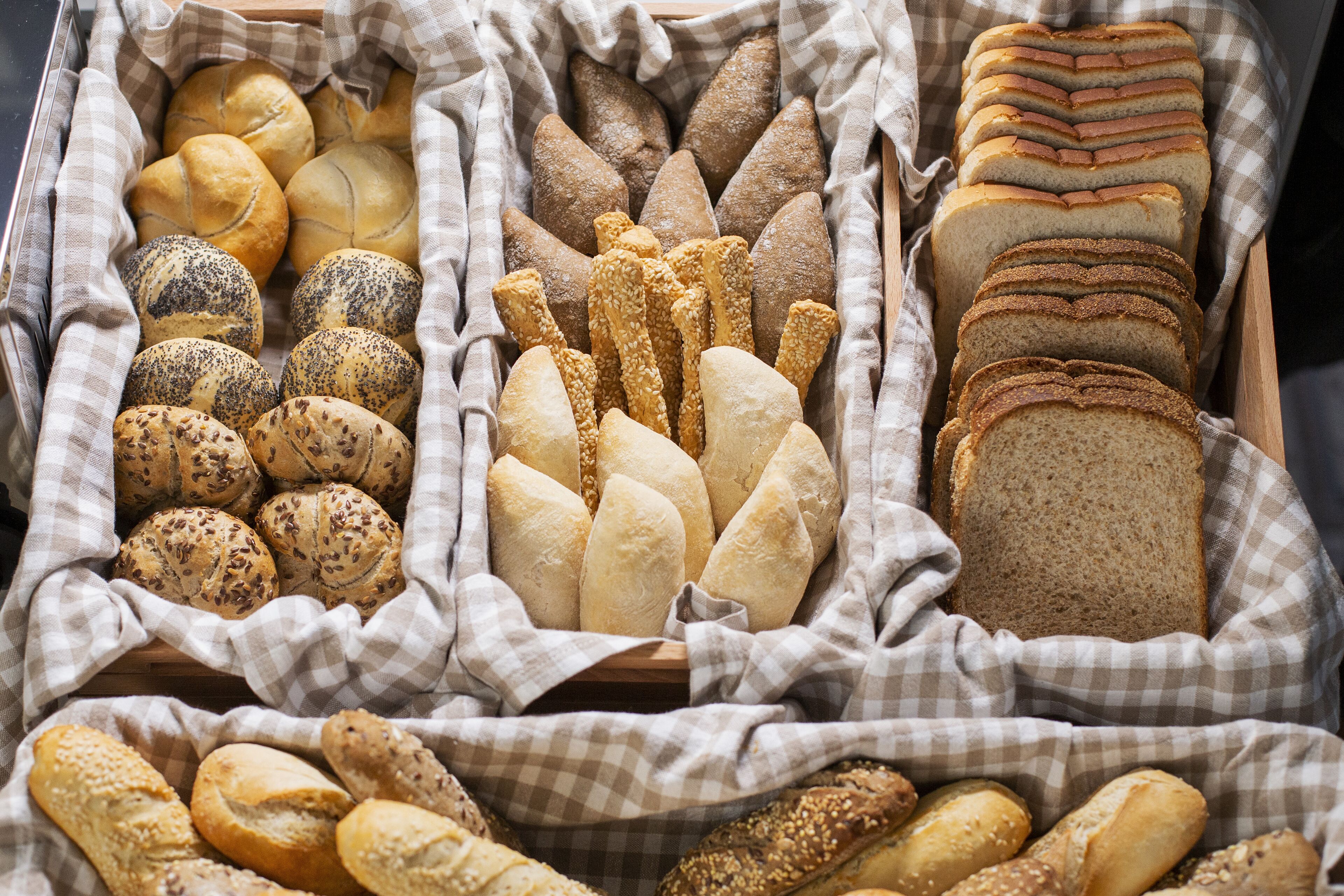 A variety of bread types in a wooden tray.