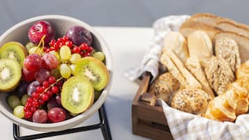 Un saladier rempli de fruits variés et un panier en bois contenant du pain.