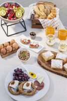 Una mesa de desayuno con diversos alimentos como huevos, pan, frutas y bebidas.
