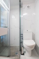 Un bagno moderno con doccia vetrata, un WC bianco e una parete in marmo.