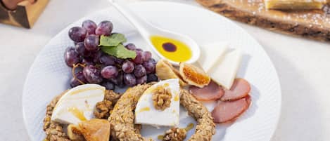 A plate with grapes, cheese, walnuts, and ham.