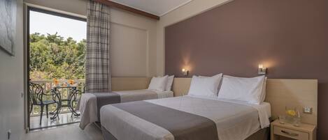 Une chambre d’hôtel avec deux lits, un balcon doté de mobilier d’extérieur et une table de chevet avec une lampe.