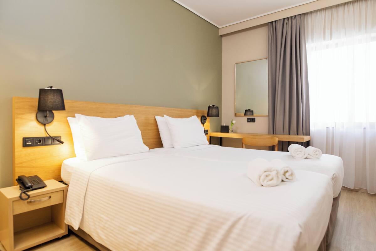 Habitación de hotel con una cama grande, mesitas de noche, lámpara, teléfono y espejo.