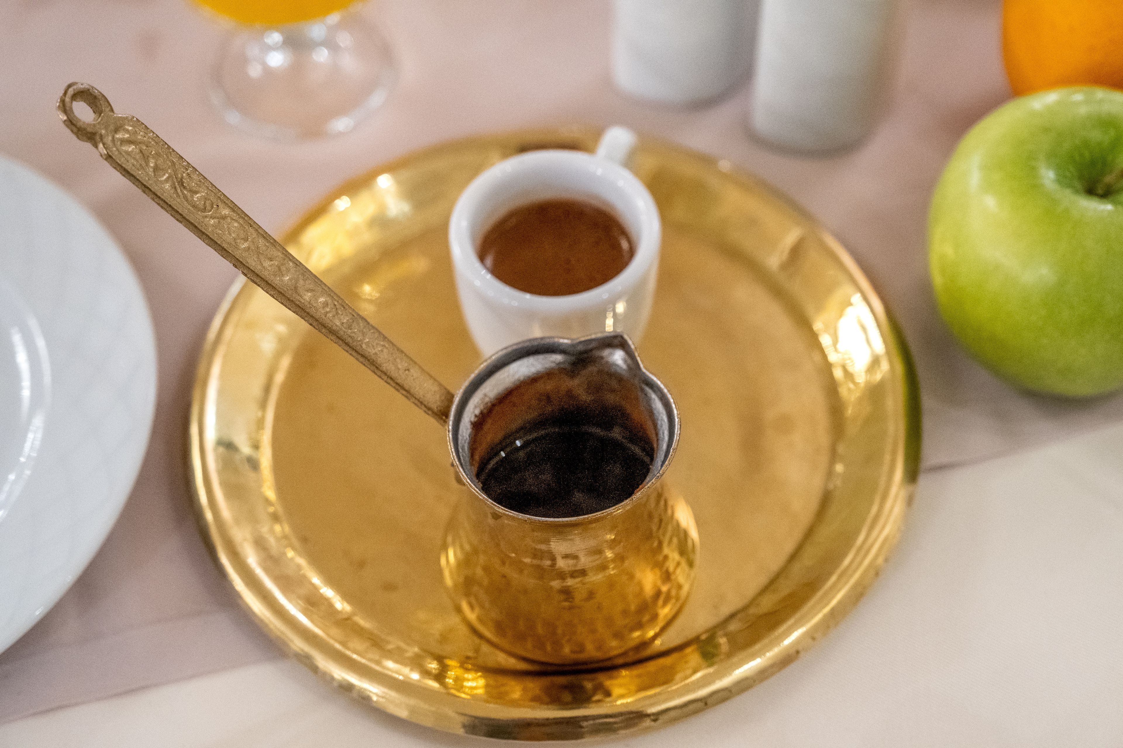 A tray with a small cup of coffee and a spoon.
