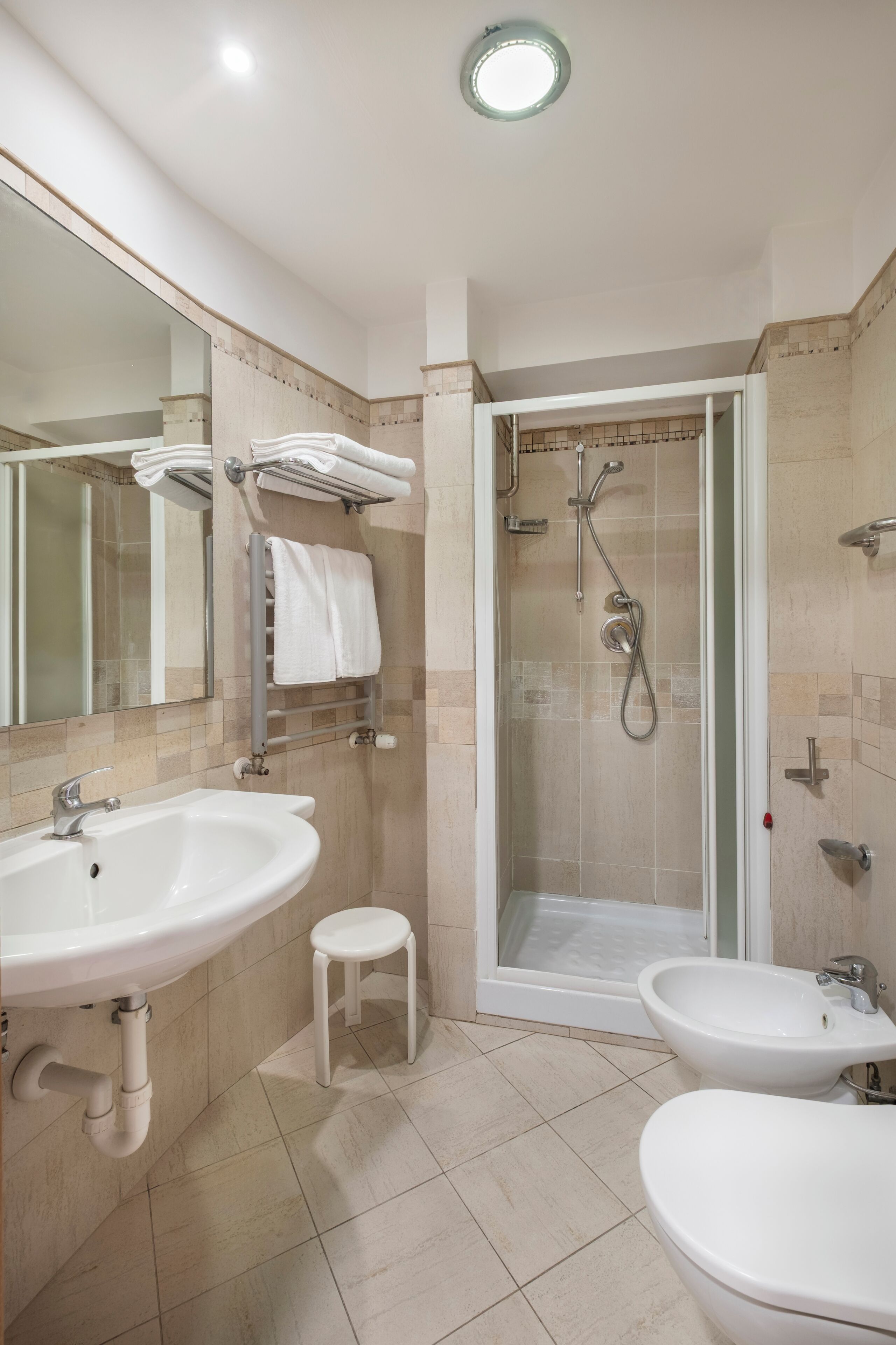 Un baño moderno con ducha, dos lavamanos y un inodoro.
