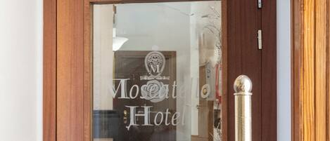 A wooden door with a glass panel, a reception sign, and a reflection of a room interior.