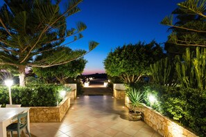 An outdoor pathway leading to a building, flanked by stone walls and various plants. - Hotel Ristorante Cavalluccio Marino (Lampedusa)